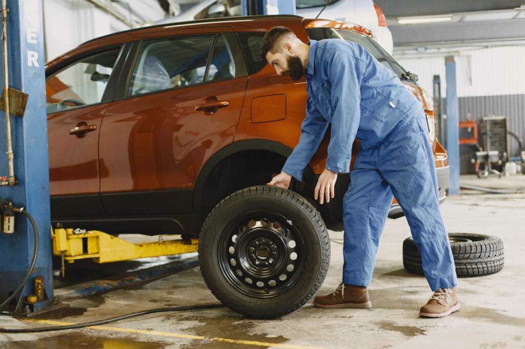 majstor u kombinezonu menja gume na automobilu